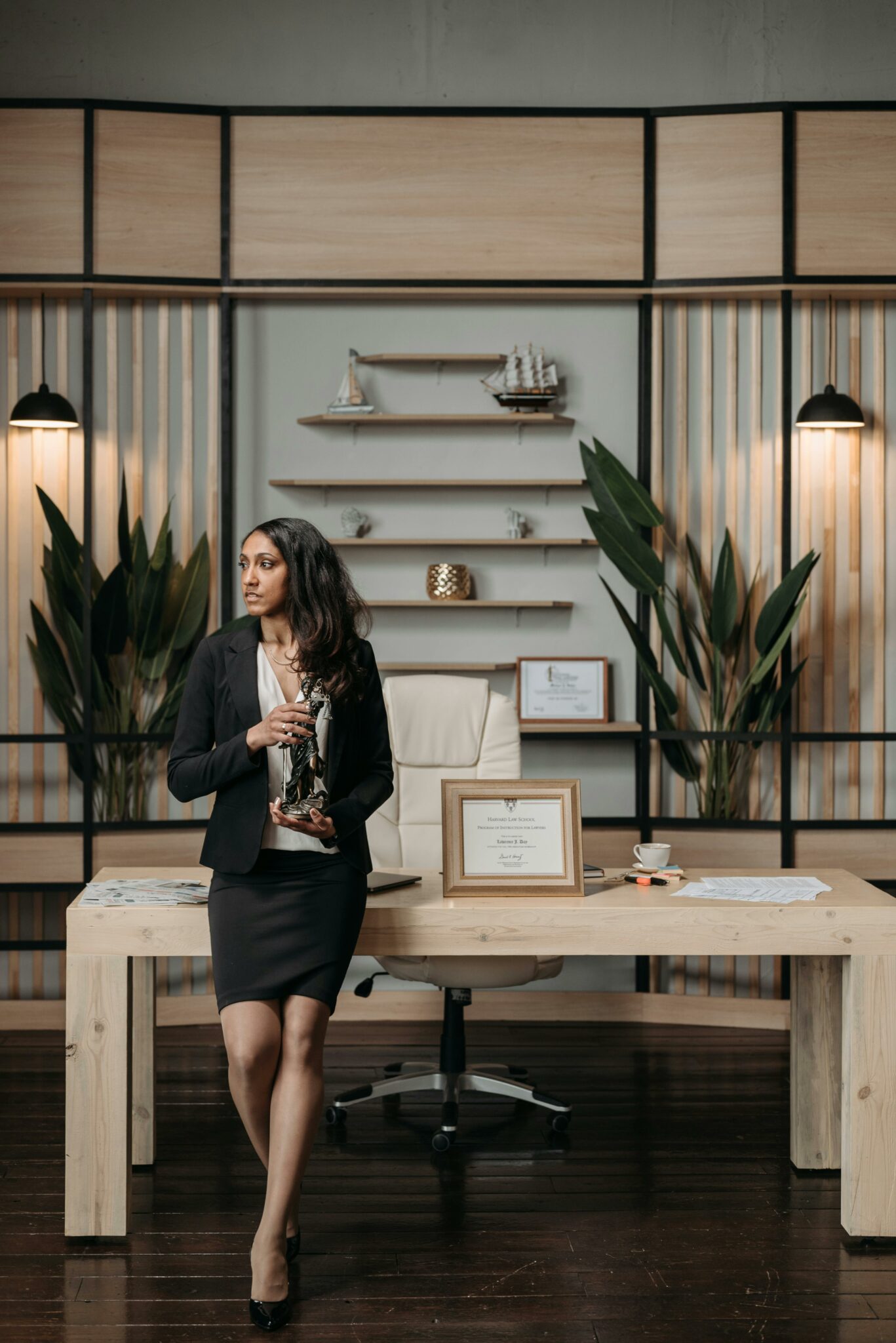 Businesswoman holding a trophy in a contemporary office with a desk and awards.